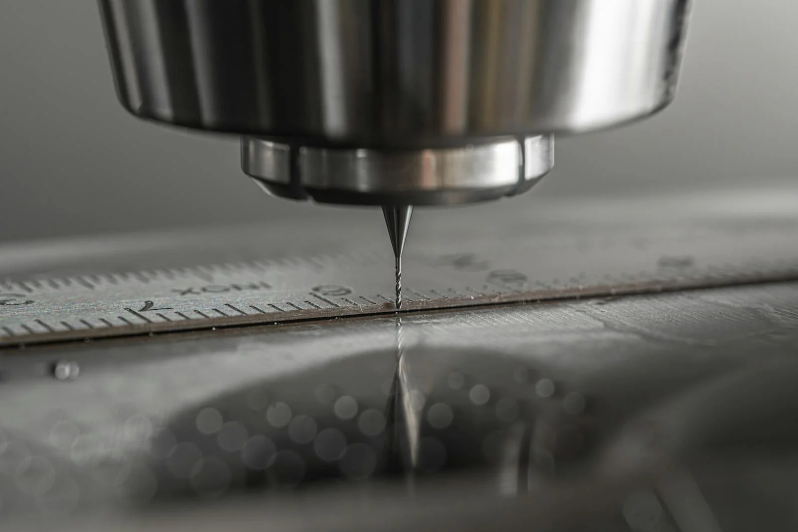 Macro close-up of a CNC milling machine end mill above a steel rule on a machined surface