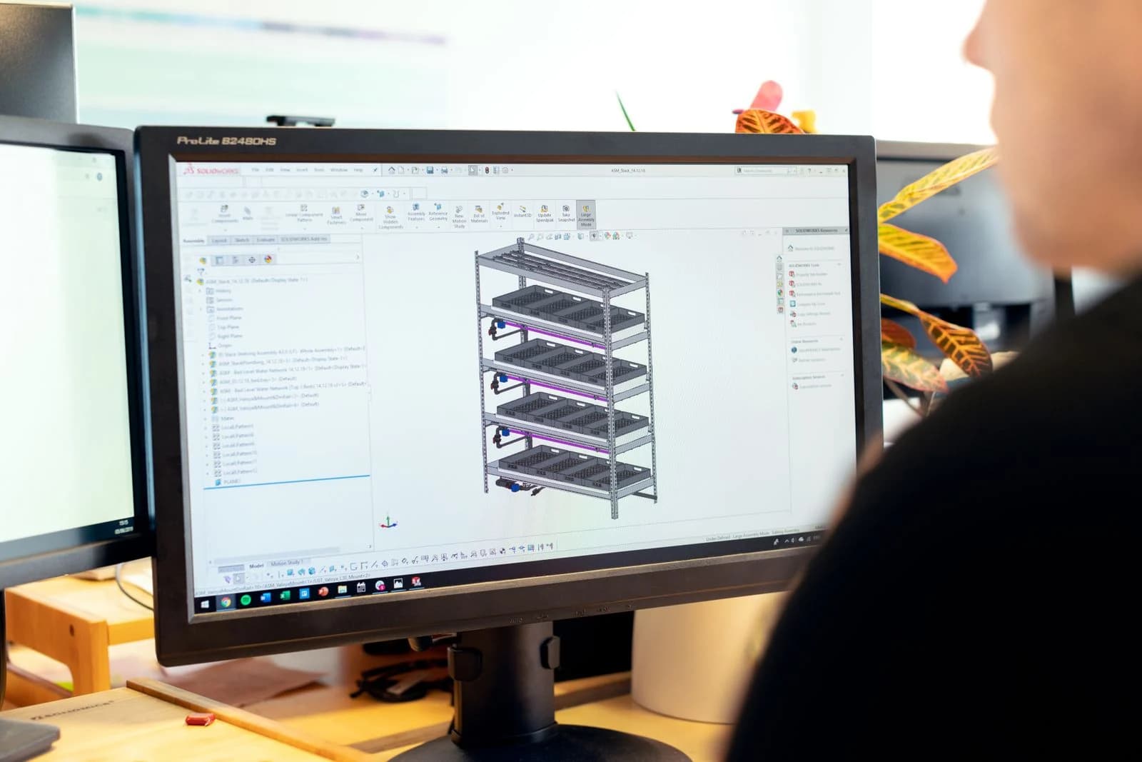 Engineer working on a parametric CAD assembly model on a desktop workstation