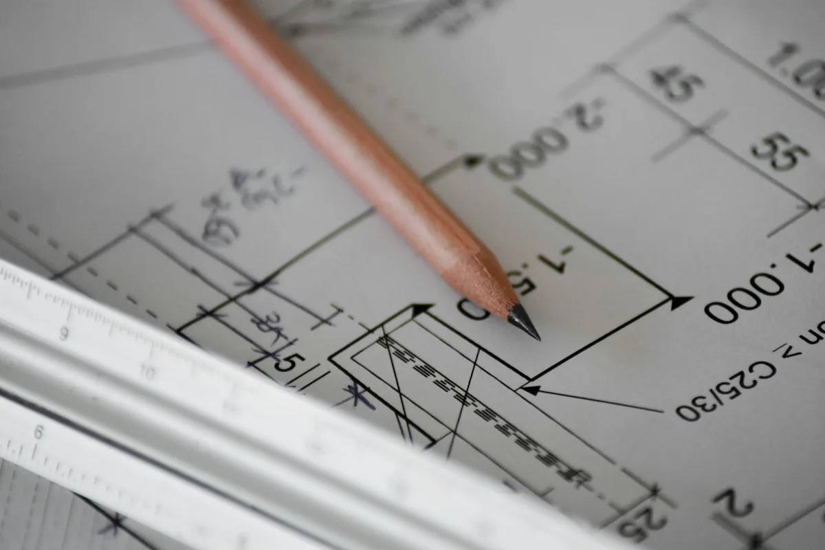 A pencil resting on a clean sheet of white paper, the starting point for a hand sketch that will be traced into vectors