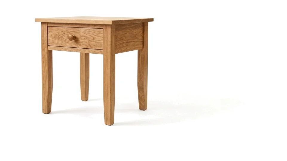 A solid oak side table with a drawer, photographed on white